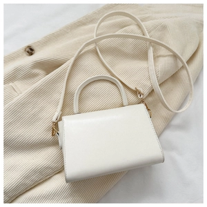 Detailed top view of white leather mini square bag with gold hardware and strap