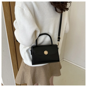 Close-up of black matte leather mini square bag featuring a gold twist lock and top handle