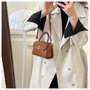 Detail of vintage caramel brown crossbody bag with gold lock and stylish handle