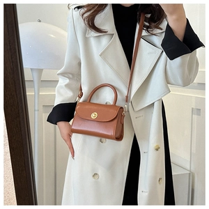 Detail view of a vintage brown leather crossbody bag with a gold metal twist lock