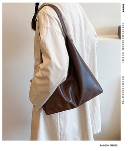 Detail of dark brown leather tote bag with vintage oil-wax texture on model shoulder