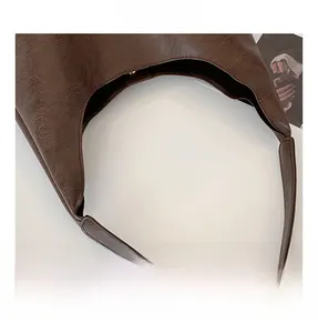 Close-up of brown faux leather tote bag with lychee texture and gold magnetic buckle