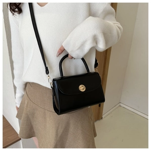 Classic black leather handbag with gold clasp shown with white knit sweater and khaki skirt