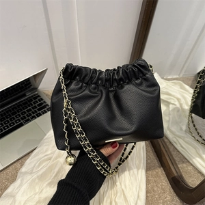 Sac à main plissé en cuir noir tendance avec bandoulière chaîne dorée porté à la main