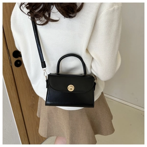 Classic black crossbody bag with gold buckle shown on model with a beige dress