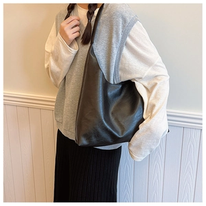 Minimalist black PU leather tote bag shown on shoulder for daily commute outfits