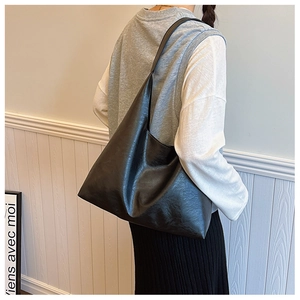Model view of a minimalist large black hobo tote bag with a glossy leather texture finish