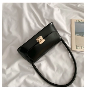 Détail d'un sac à bandoulière rectangulaire noir avec un fermoir en métal doré