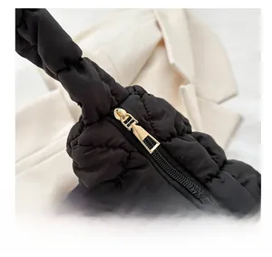 Detail of smooth gold zipper on black quilted cloud bag with pleated texture finish