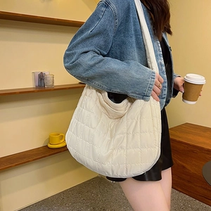 Quilted cream puffer tote bag shown on a model in a warm cafe setting for daily wear