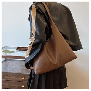 Detailed view of deep brown large-capacity hobo tote bag worn as a shoulder bag