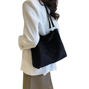 Large black quilted tote bag with V-shaped texture and faux leather straps for work