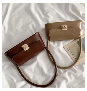 Détail de sacs portés épaule baguette vintage marron et beige avec boucles métalliques dorées