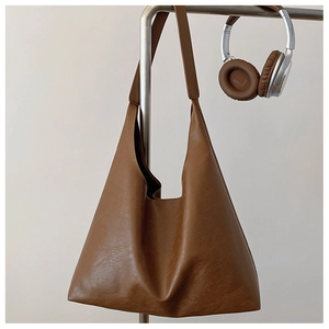 Detail of a brown leather Hobo tote bag showing its soft texture and wide shoulder strap