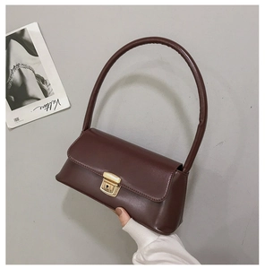 Détail d'un sac à main en cuir bordeaux vintage avec de longues anses rondes et boucle dorée