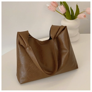Detail of a dark brown tote bag with unique twisted knot handle in a lifestyle setting