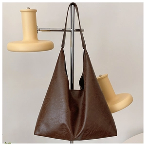 Detail of dark brown tote bag with vintage cracked leather texture and long straps