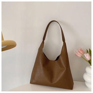 Close-up of a minimalist dark brown leather tote bag on a stylish white table setting