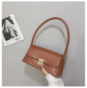 Détail macro du sac sous le bras en cuir marron avec une boucle rectangulaire dorée