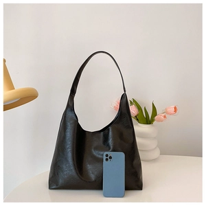 Detail of black faux leather tote bag with vintage wrinkled texture on a white table