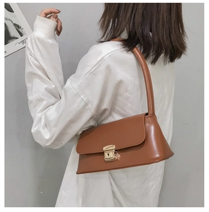 Gros plan d'un sac bandoulière en cuir marron avec fermoir métallique doré et rabat
