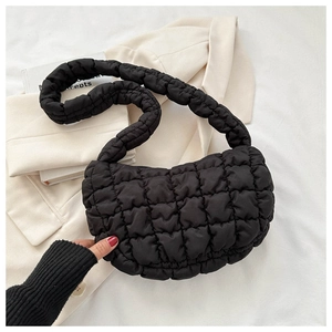 Macro detail of black quilted cloud bag with puffy grid texture and shoulder strap