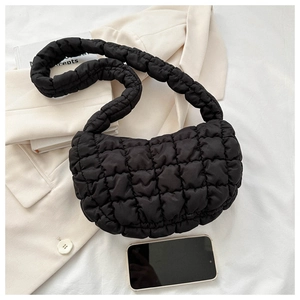 Detail shot of black quilted checkerboard tote bag next to a smartphone for size scale