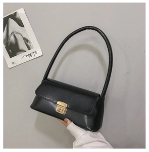 Détail du sac baguette en similicuir noir avec une élégante boucle métallique dorée