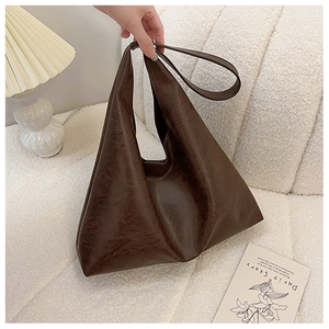 Detail of dark brown faux leather tote bag with vintage texture on a white sofa