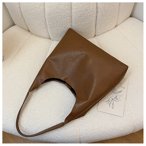 Close-up of deep brown hobo bag showing premium leather texture on a white chair