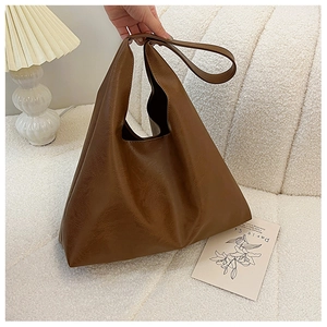 Close-up of brown faux leather tote bag with soft texture on cream velvet background