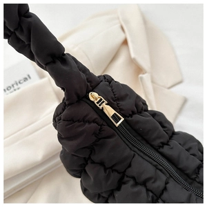 Close-up of black quilted cloud bag with gold zipper and puffy texture details