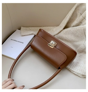 Détail d'un sac sous le bras marron vintage avec un fermoir doré et un cuir synthétique mat