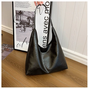 Detail shot of black leather tote bag with glossy texture and wide bottom