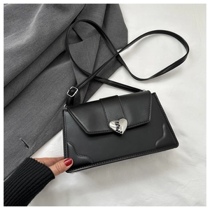 Detail shot of silver heart-shaped metal clasp on black leather envelope bag