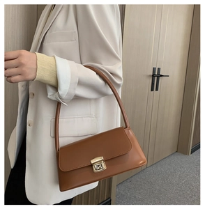 Gros plan du sac sous l'aisselle en cuir caramel avec boucle dorée en métal