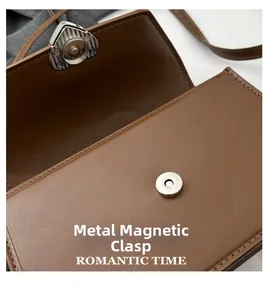 Macro detail of brown leather bag featuring a heart-shaped magnetic clasp and fine stitching