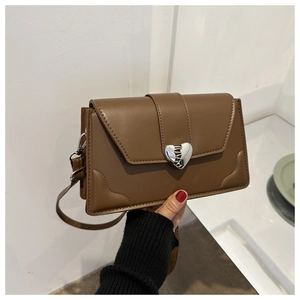 Detail of silver heart clasp and textured brown PU leather on a small crossbody bag