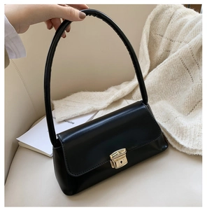 Détail du sac baguette noir avec fermoir doré rectangulaire et texture cuir lisse