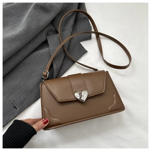Close-up of vintage brown crossbody bag featuring a silver heart-shaped textured metal lock