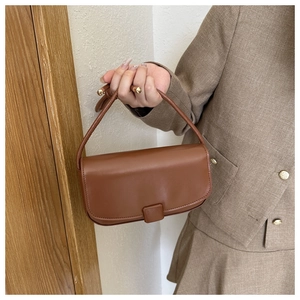 Detailed close-up of a brown PU leather handbag with elegant gold metal handle accents