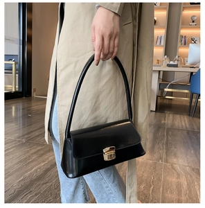 Détail d'un sac sous le bras en cuir noir brillant avec un fermoir rotatif doré vintage