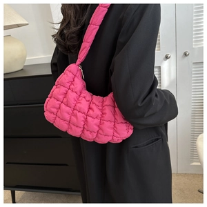 Side view of a bright pink quilted puff bag worn over a black blazer for chic contrast