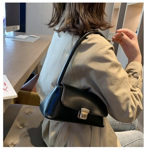 Vue latérale du sac porté épaule en cuir noir avec boucle dorée sur un mannequin
