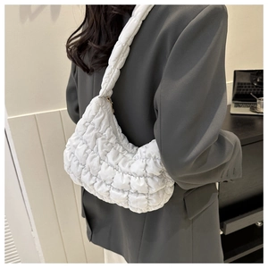 Detailed back view of a white quilted dumpling shoulder bag worn by a model in a minimal room
