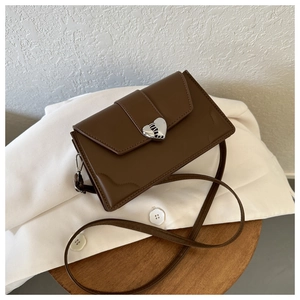 Macro view of vintage brown crossbody bag with silver heart-shaped metal clasp details