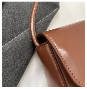 Close-up of brown leather bag showing premium stitching and strap connection details
