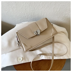 Detail of elegant heart-shaped silver lock on cream leather crossbody bag surface