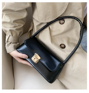 Détail du sac baguette noir en cuir souple avec un fermoir tournant rectangulaire doré