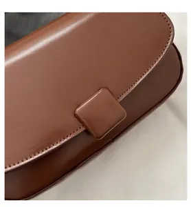 Detail of dark brown faux leather flap bag featuring a square magnetic buckle and fine stitching